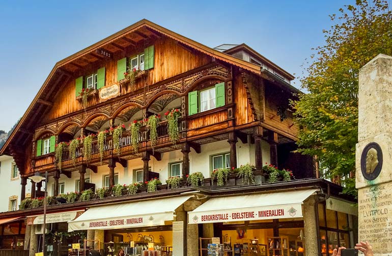 Wooden house with green leafy shrubs overhanding the railings at Königssee