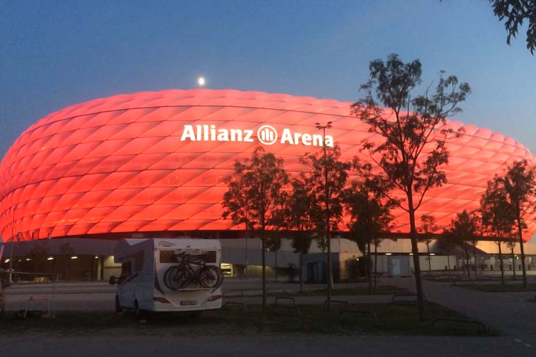 Allianz Arena lit up in red at night in the motorhome parking munich Germany