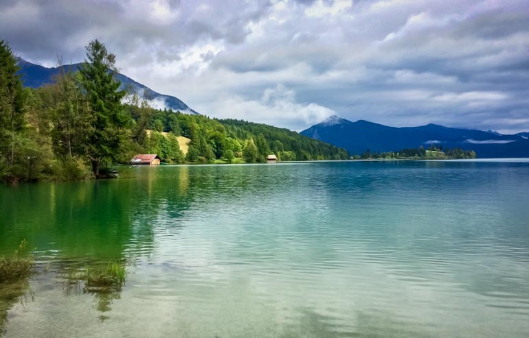 Walchensee, Germany - a lake with pin trees and small buildings on the edge