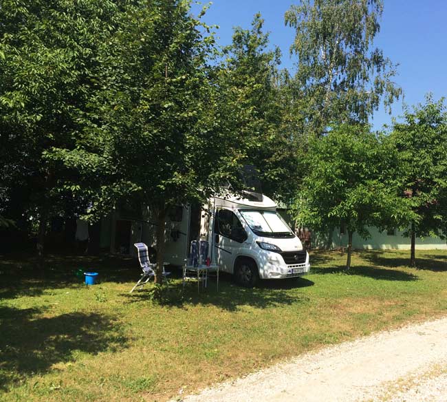 motohome parked at a campsite under trees 