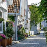 white timber houses with flowers growing in pots and hanging baskets