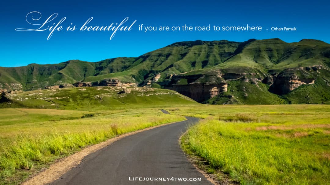 Road trip quote on an image of a road heading towards green mountains. 