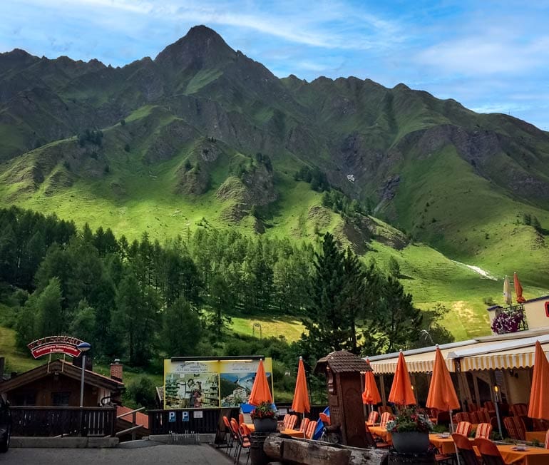 cafe with outside tables with a backdrop of green mountains and forests