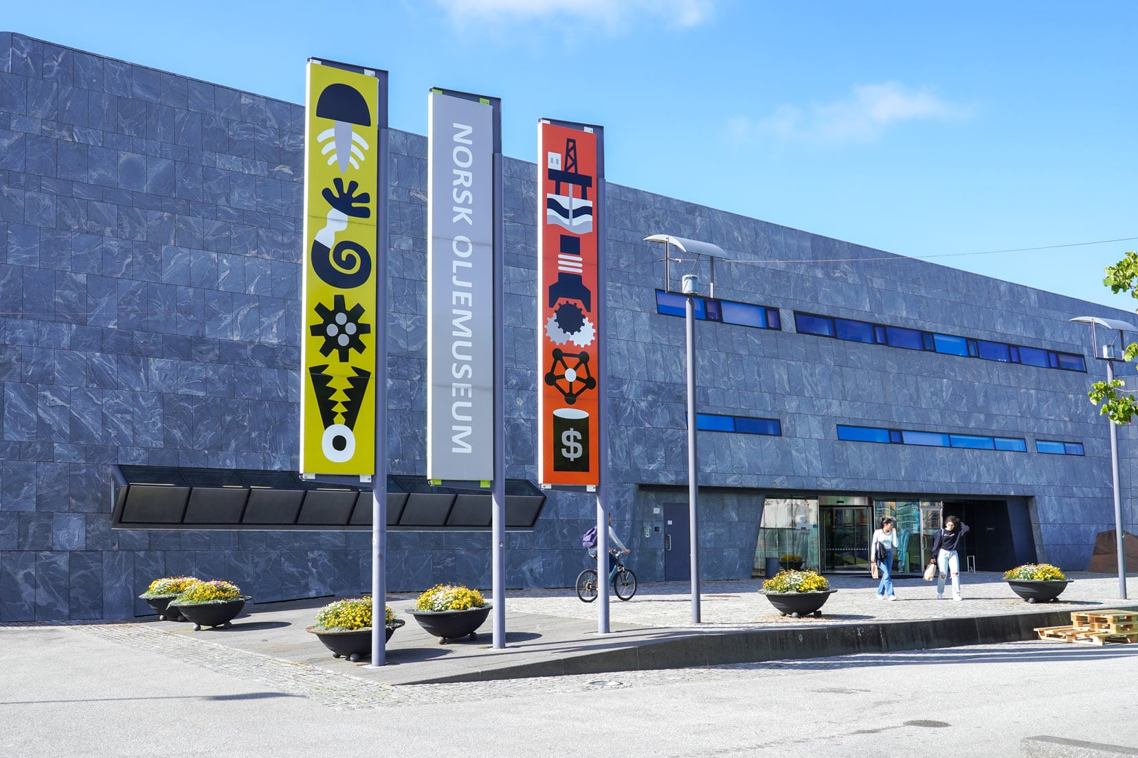 Outside of the Stavanger Oil Museum - a grey concrete coloued building with three coloured flags outside