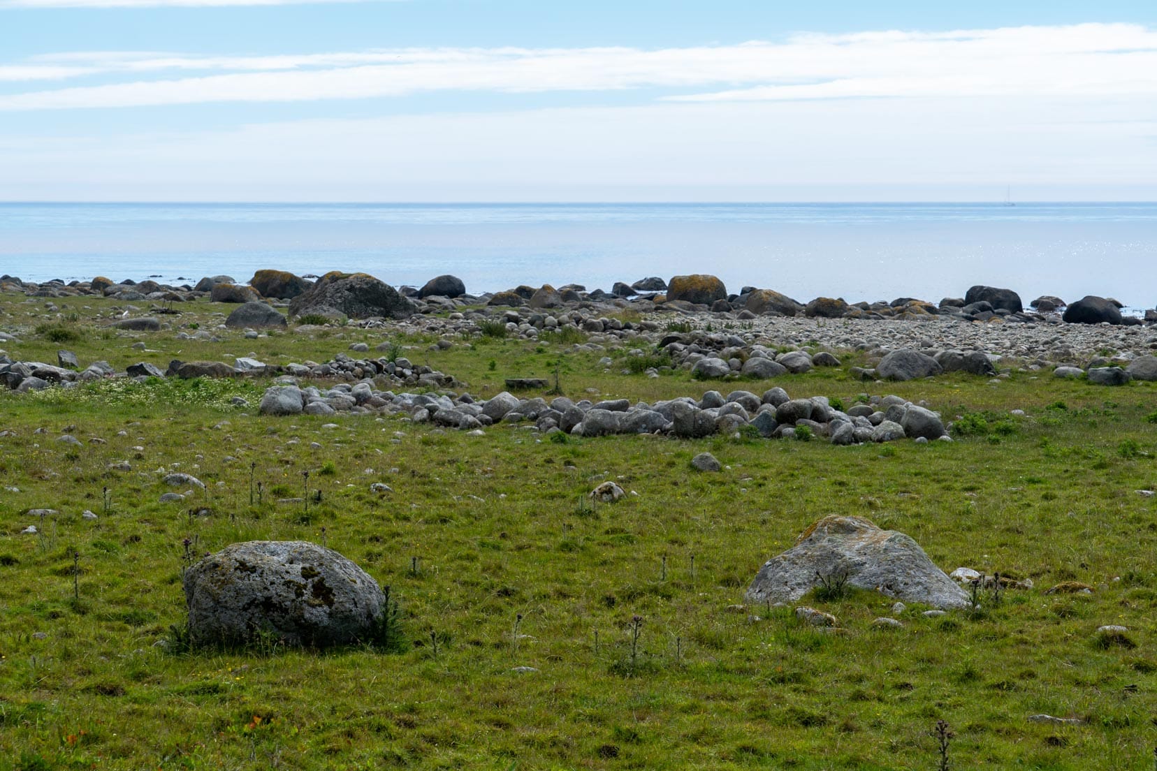 Old burial grounds and ancient settlement - granite stones set out on the grass near the shore