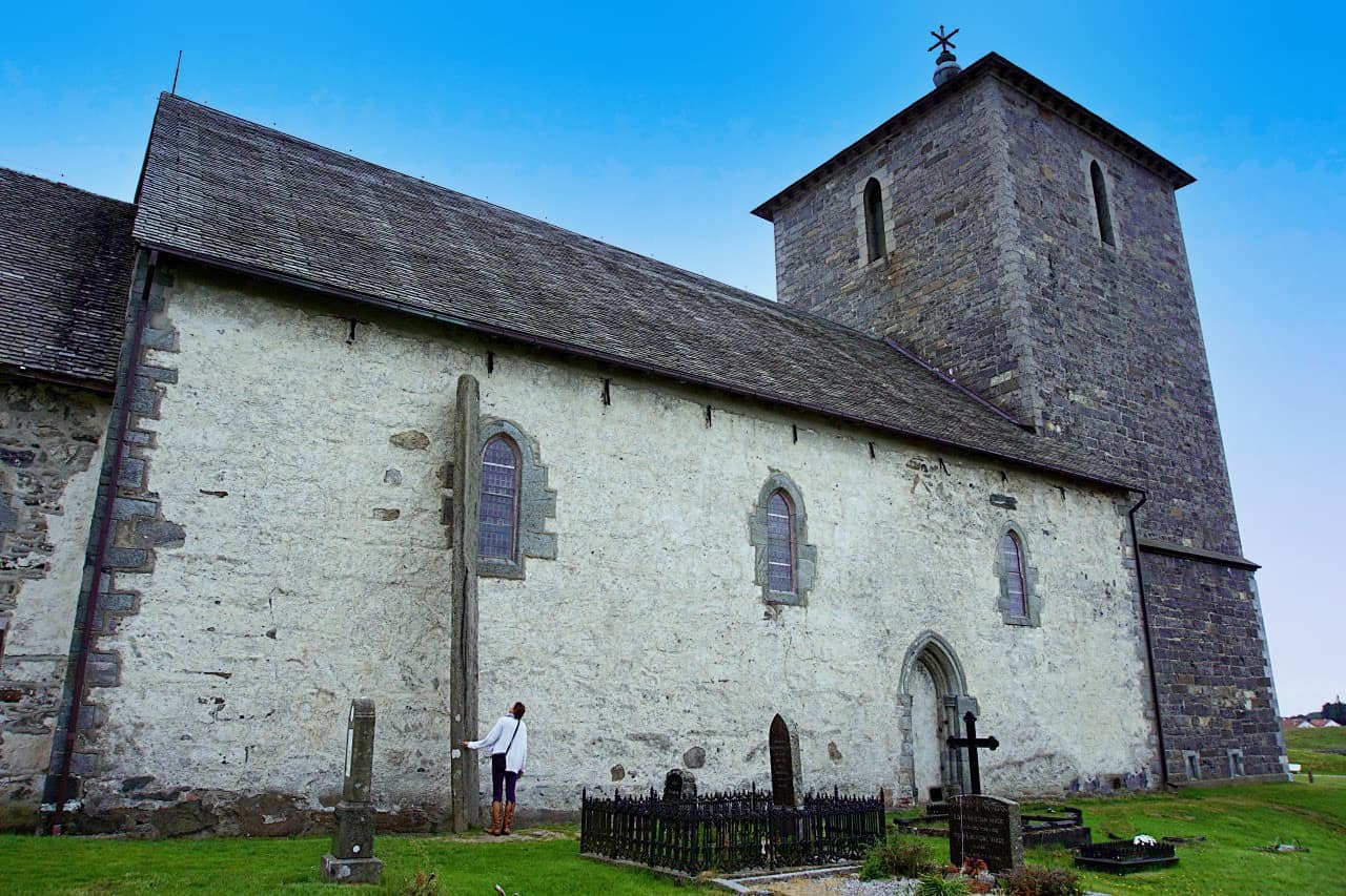avaldsnes church with a stone leaning towards the church