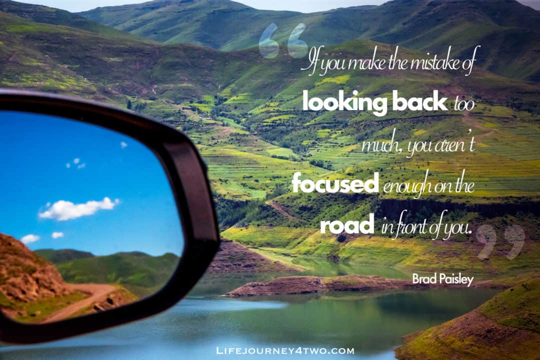 Road trip quote on a photo of mountains and lake with car wing mirror in view with bend in the road