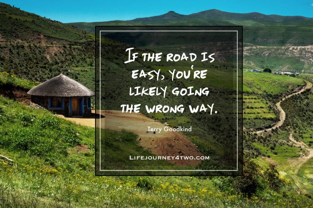 Quote on green fileds with a n Africa hut and a windy dirt road
