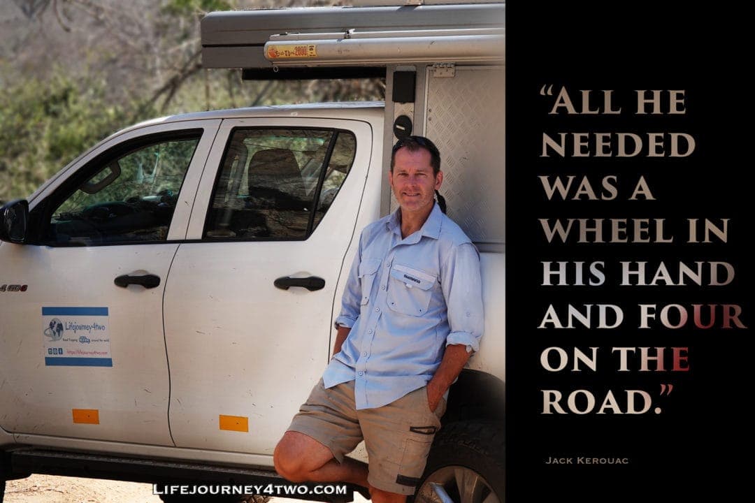 Lars standing by car with road trip quote