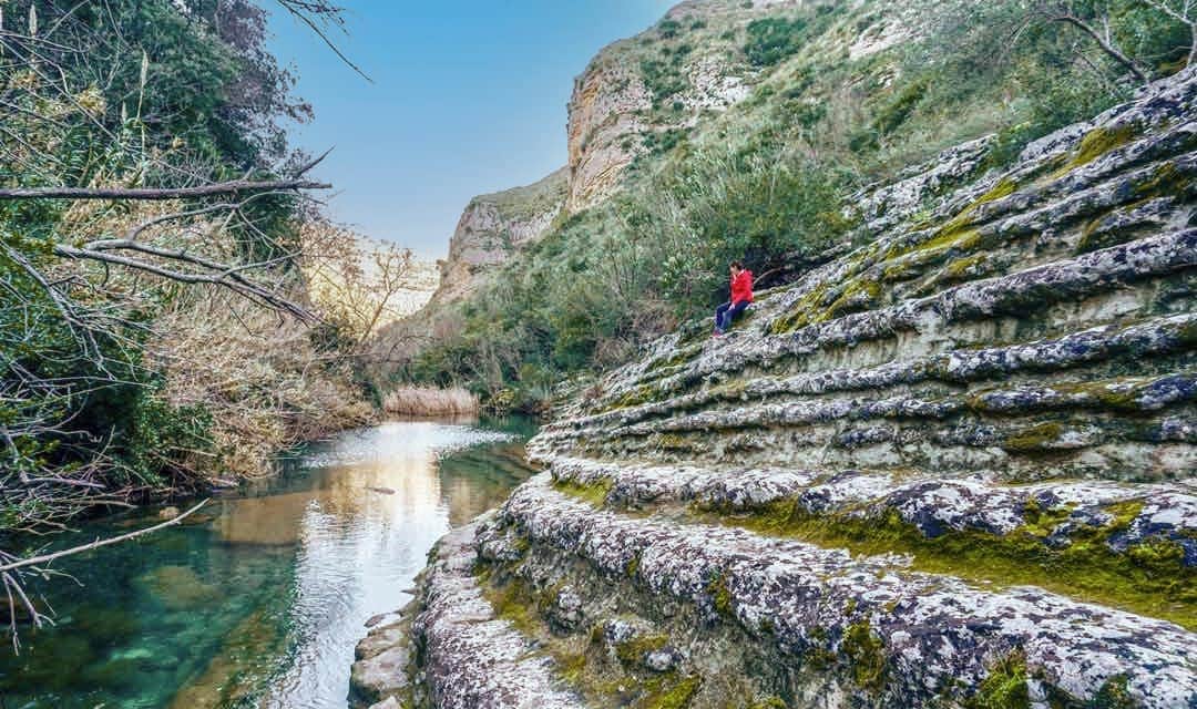 woman sat on steps in cavagrande cassibile canyon by water