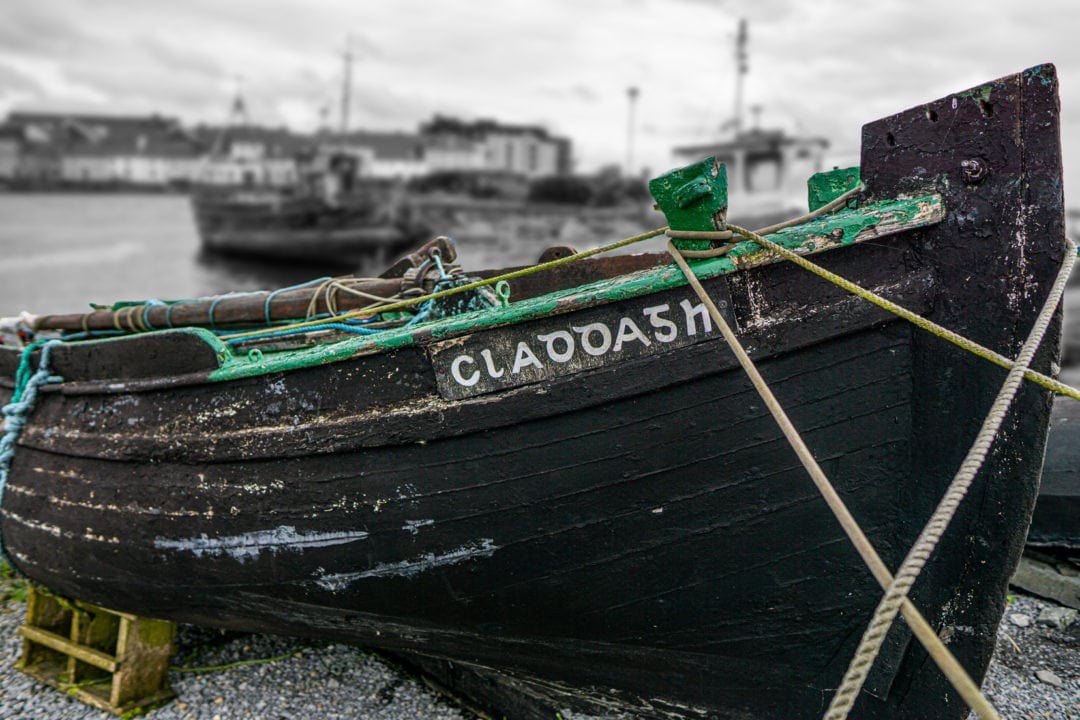 Ireland Landscape Photography: old black wooden fishing boat moored with ropes on the beacj