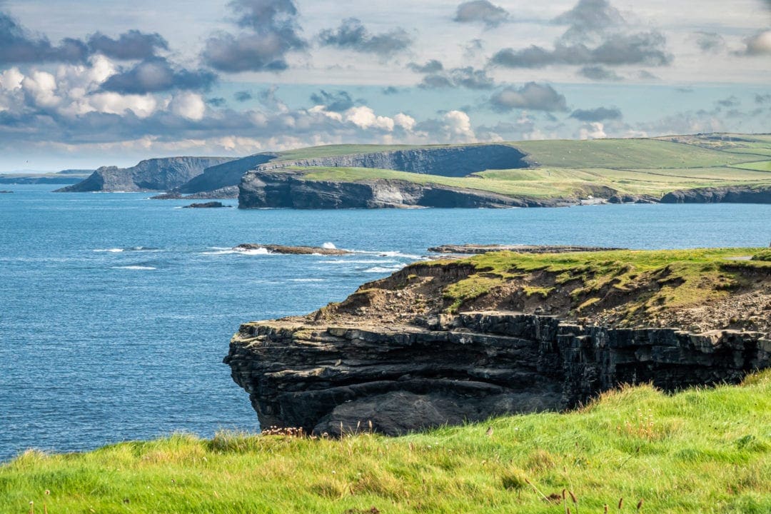 Ireland Landscape Photography: Green grassy plateau with steep cliffs that drop into the blue ocean