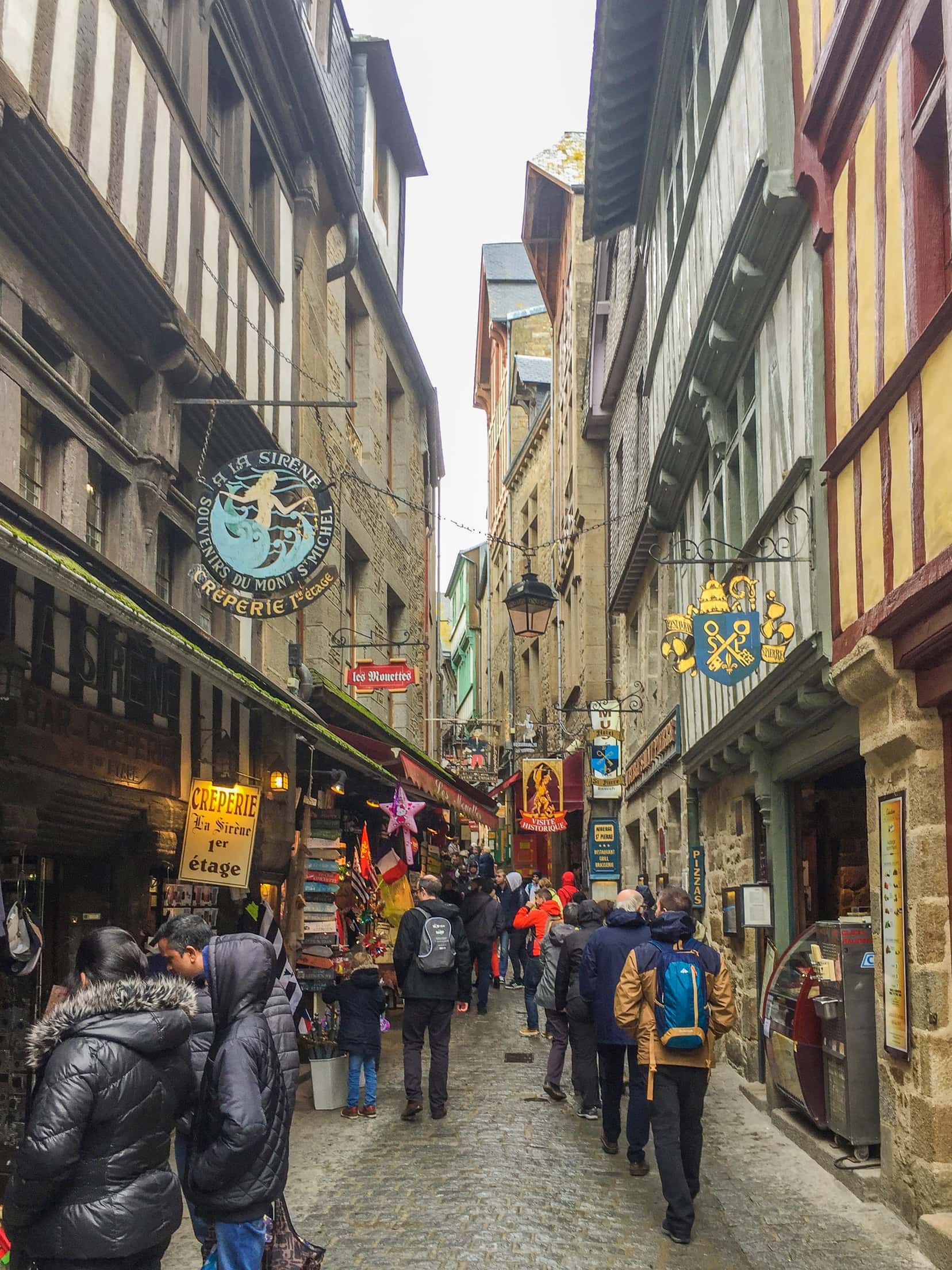 People in a busy narrow street surrounded by tall old buildings