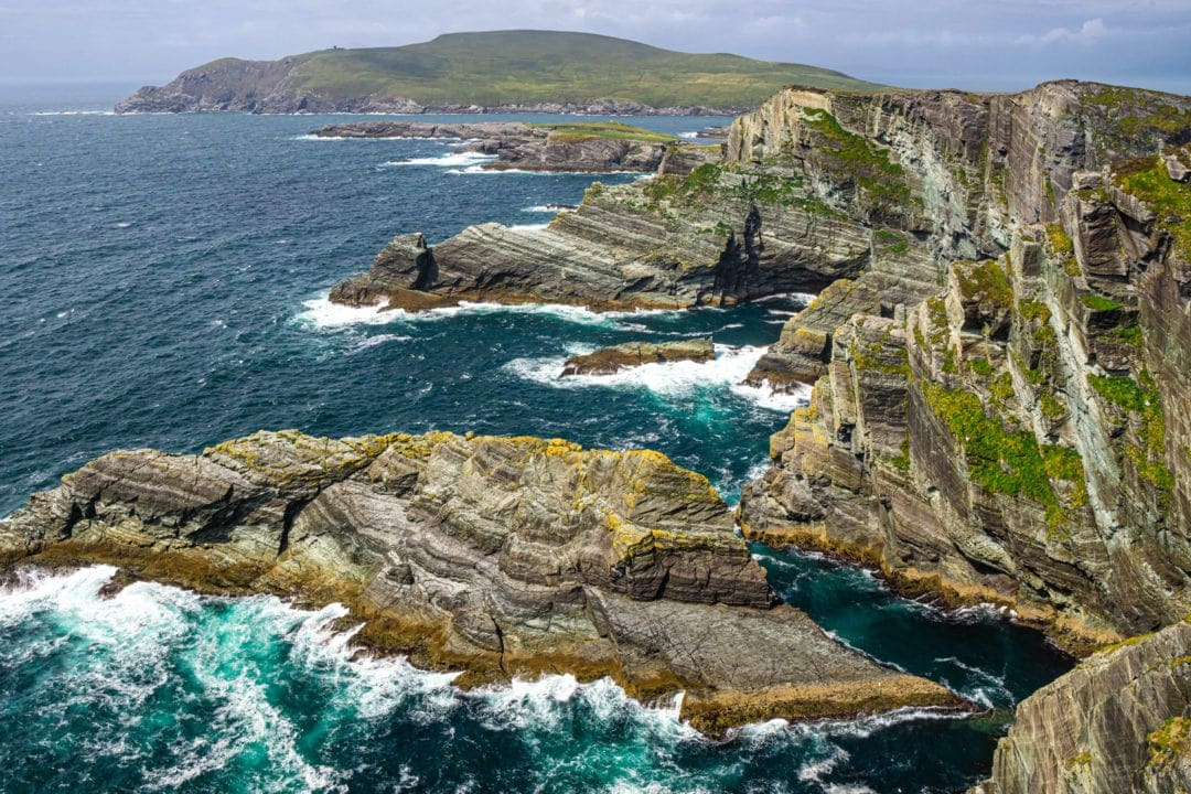 Ireland Landscape Photography: Rocky cliffs made of layered stone with a green ocean below