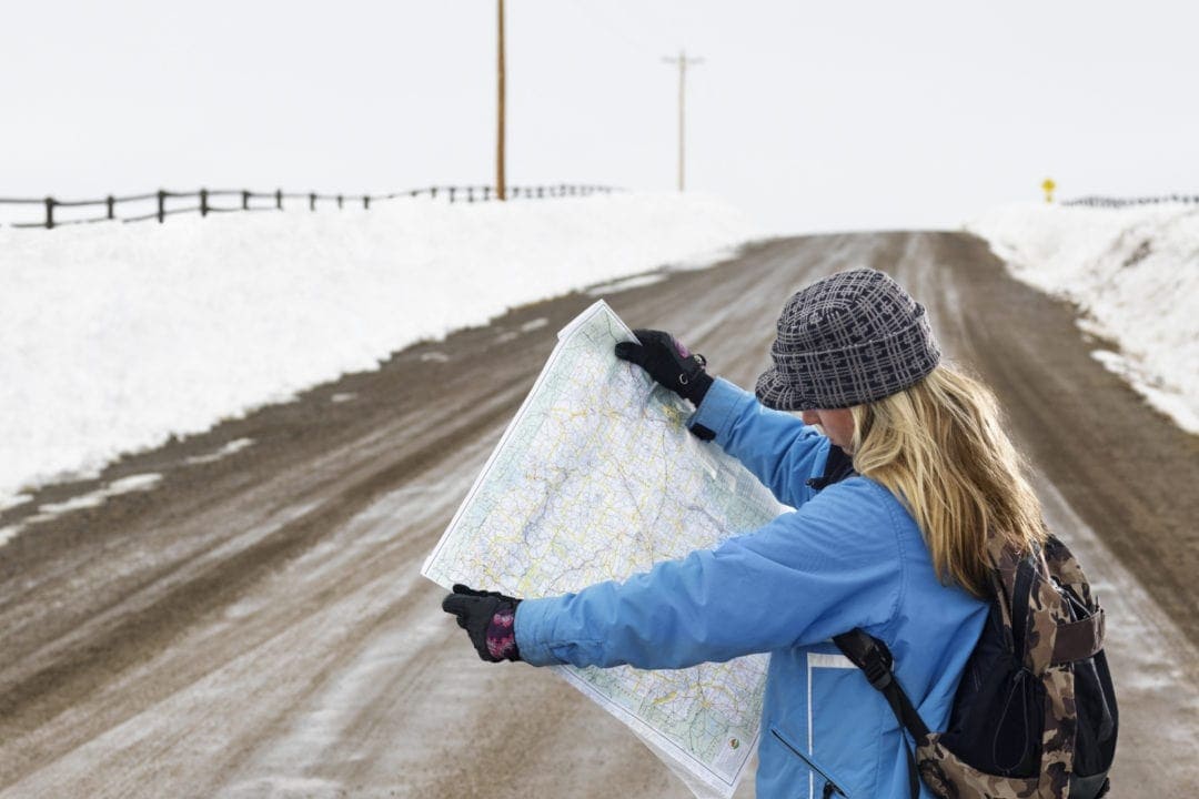 Girl reading a map in the snow - couples road trip tips