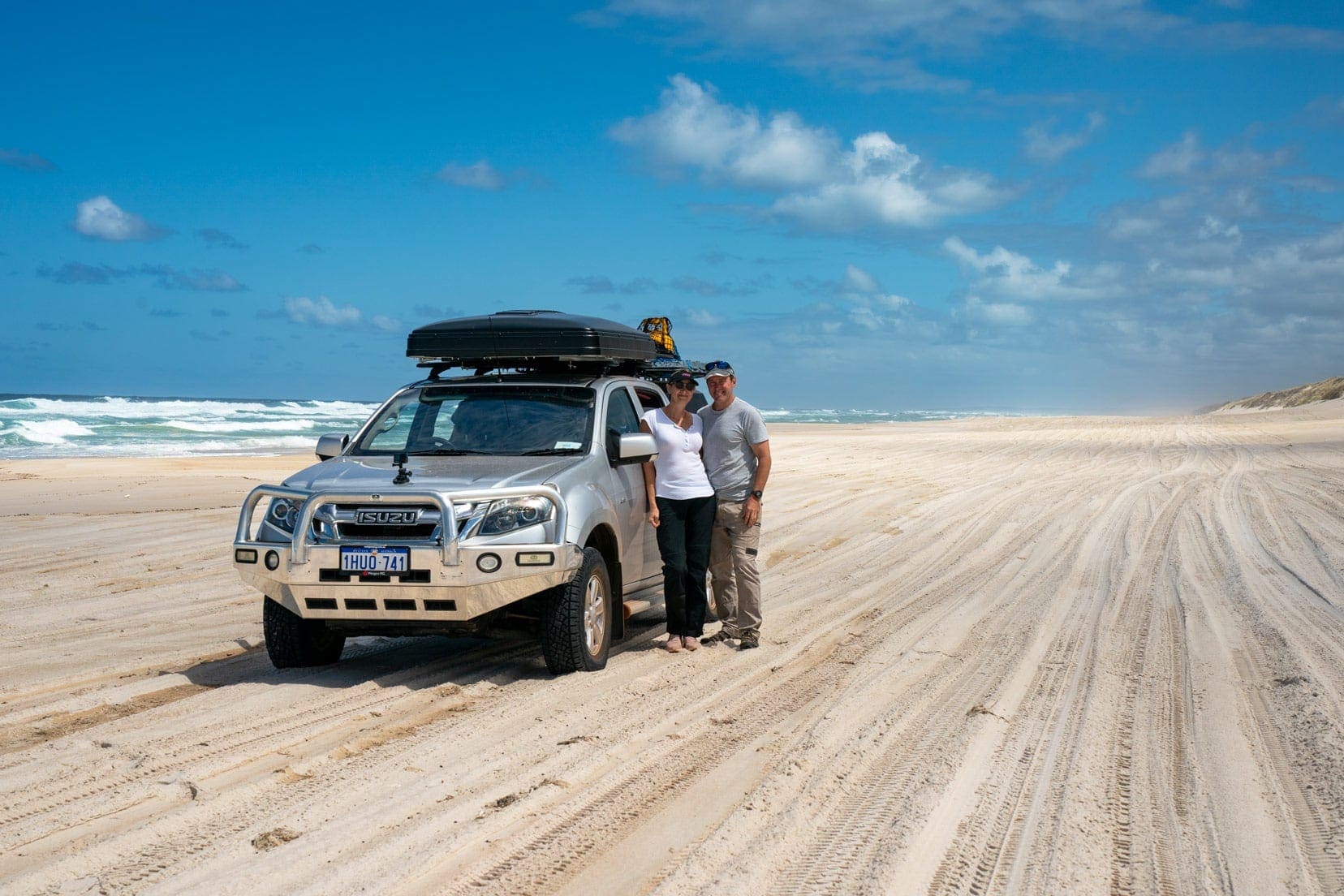 Road Trip Tips for Couples header image of Shelley ad Lars of Lifejourney4two stood by their 4x4 on a beach