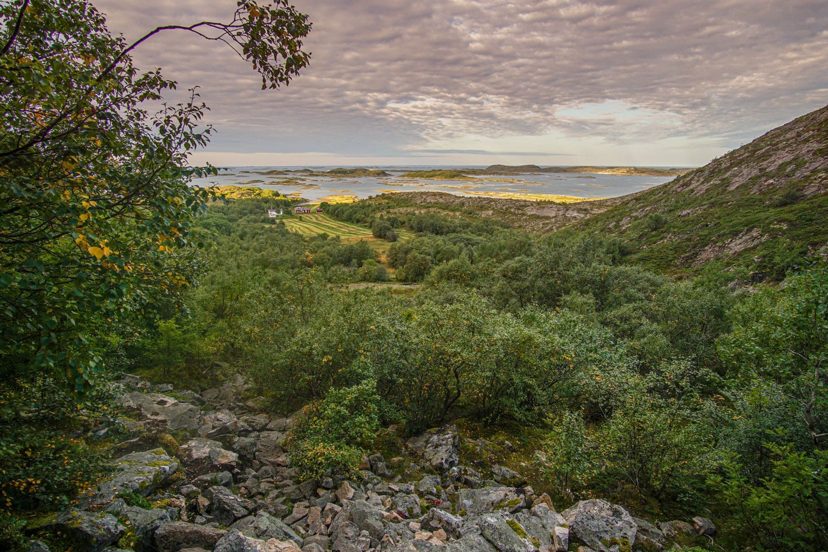 view-at-sunset-looking-down-onto-a-red-farmhouse-at-the-sea