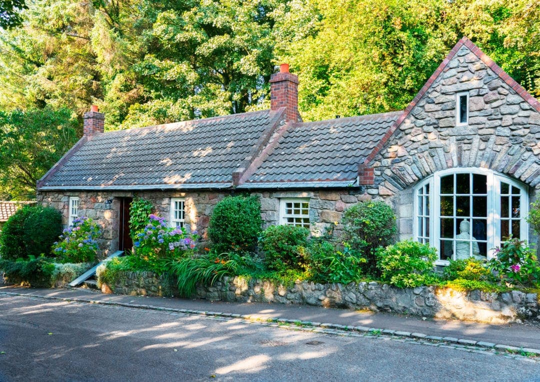 old granite cottage with lots of greenery 