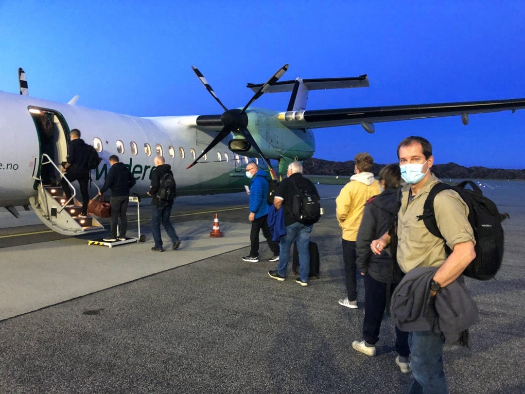 queue of people boarding a small airplane