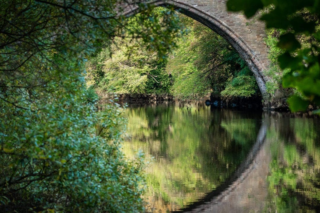 Close up of the Balgownie bridge with a reflection in hte water of the arch forming a circle