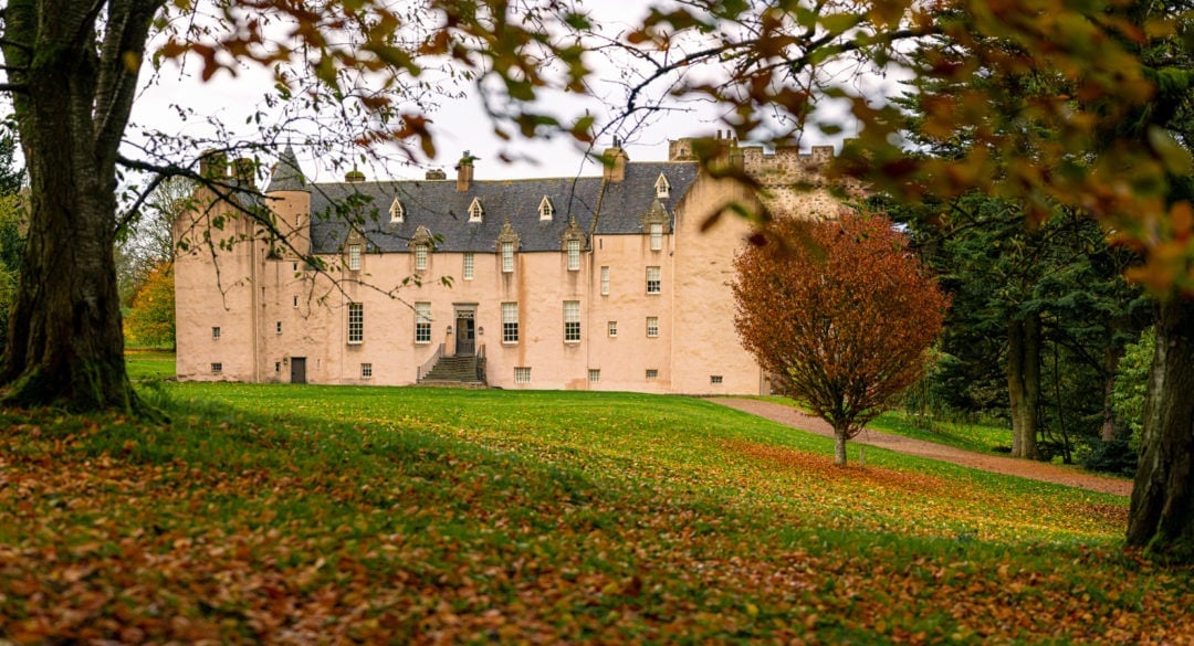 Back view of Castle Drum with autumn trees and leaves on the ground