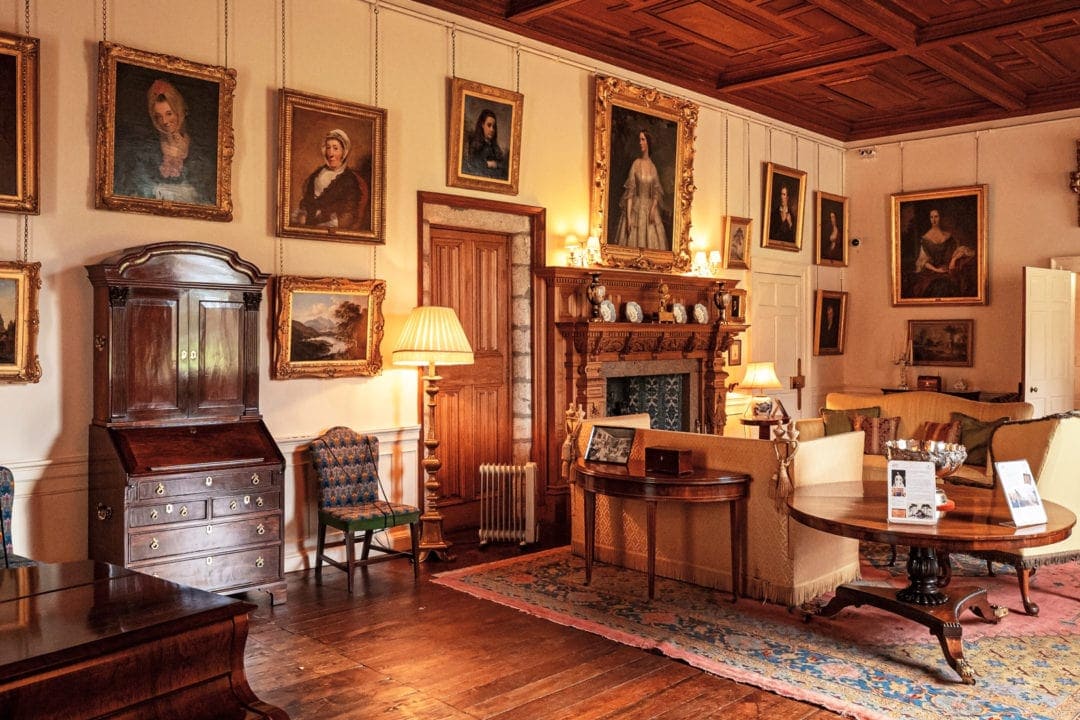 The grand hall of Castle Drum with portraits of the lord and ladies covering the cream walls. 