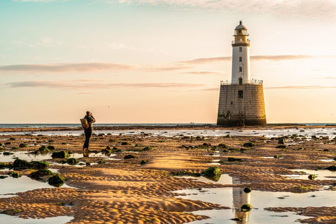 Rattray Head Lighthouse at low tide showing ridged sand and pools of water in fron of the lighthouse built on a rock tower