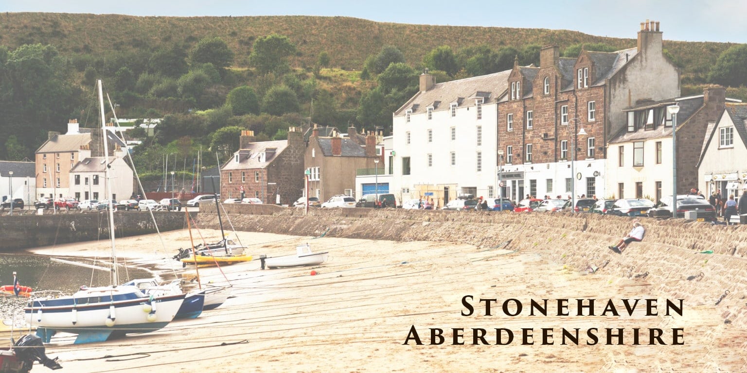 Things to do in Stonehaven Header - harbour with old buildings overlooking sand and boats with tide out