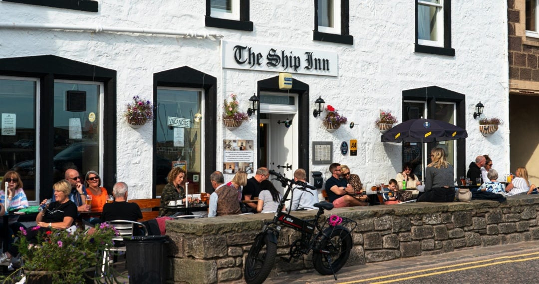 black-window-frames-and-white-walls-Ship-Inn-with-people-sat-outside-at-tables-