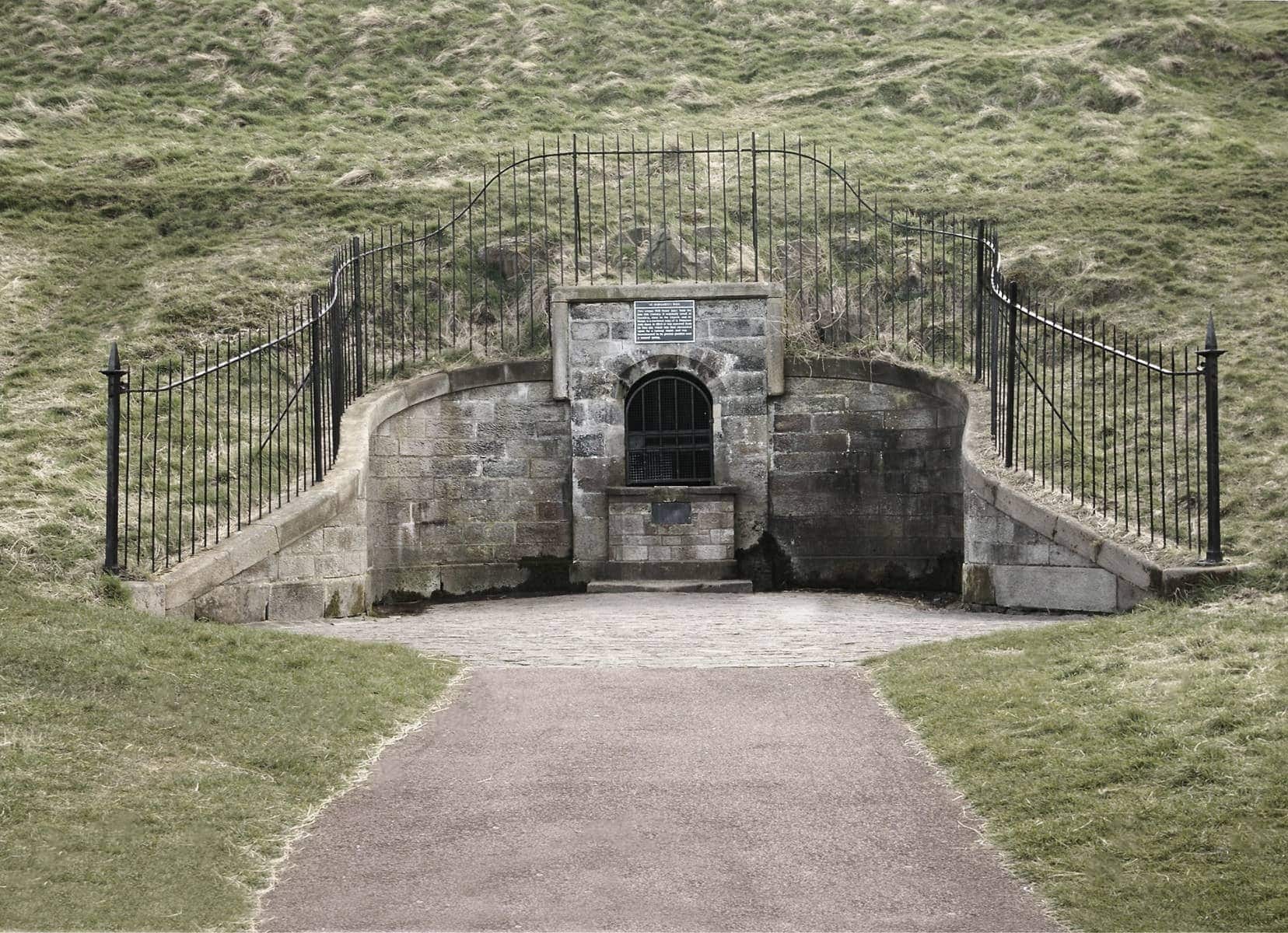 Black railings either side of a bricked area of a well