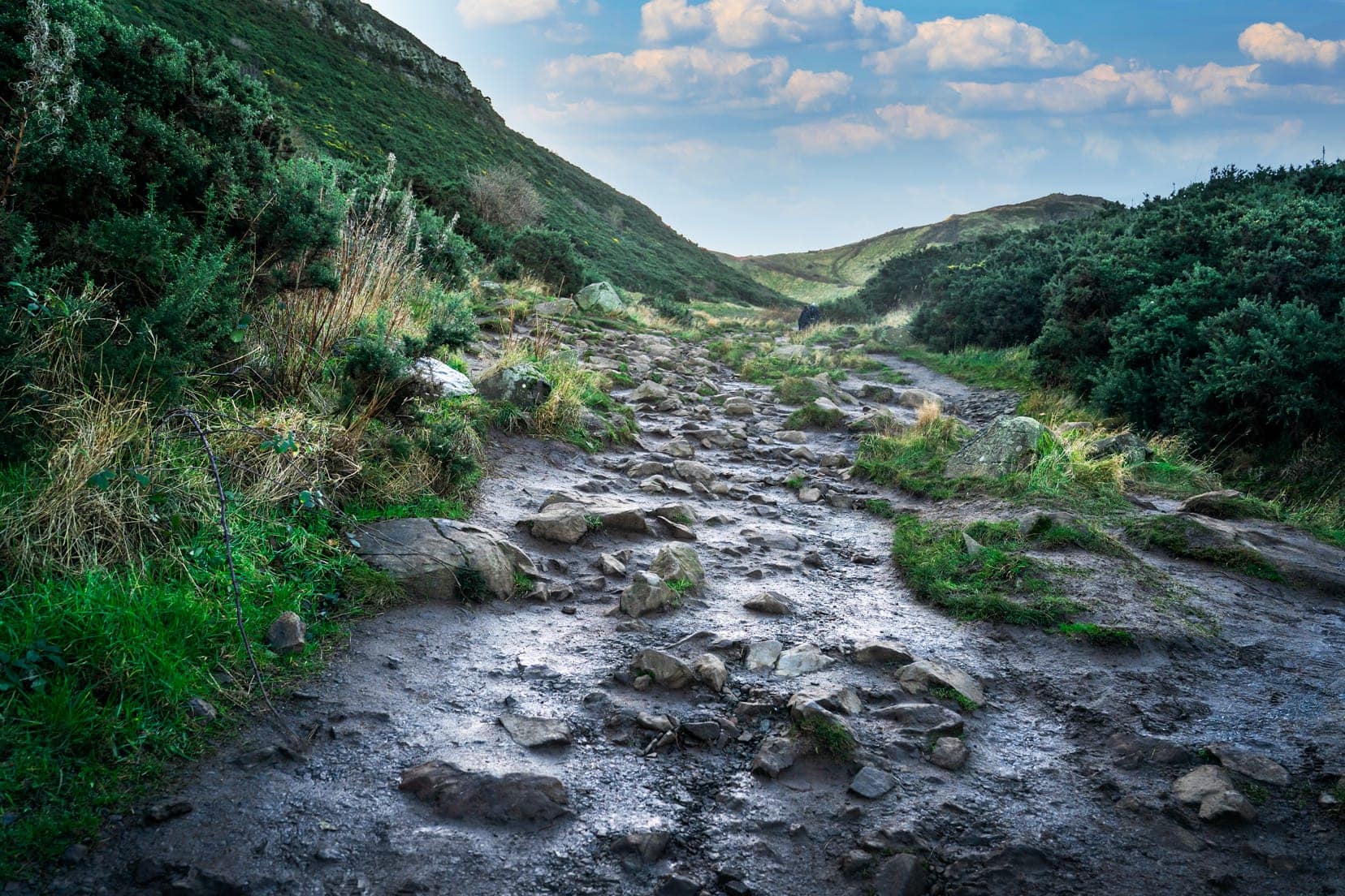 stoney and muddy pathway between green hills