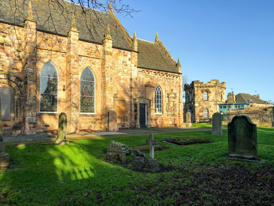 Duddingston Kirk with green grassed foreground with a few old gravestones