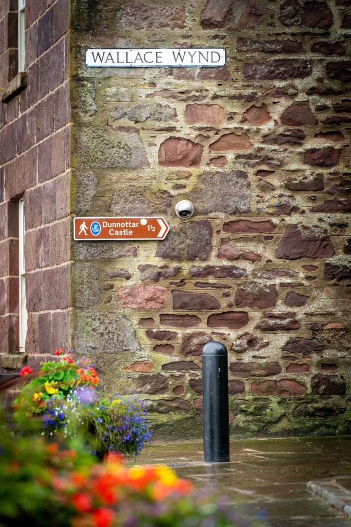 Sign for Dunnottar castle on a wall at Wallace Wynd 