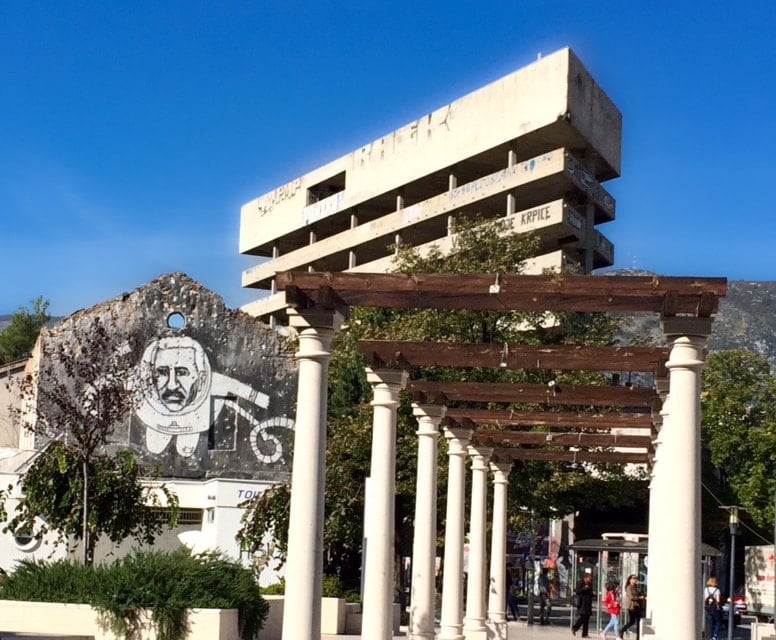 Mostar sniper tower in the background with street art on the side of a derelict buiding