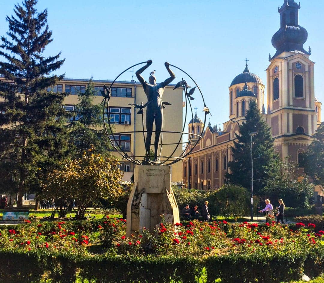 multiculture man builds the world statue in Sarajevo - a man holding a globe with doves attached 