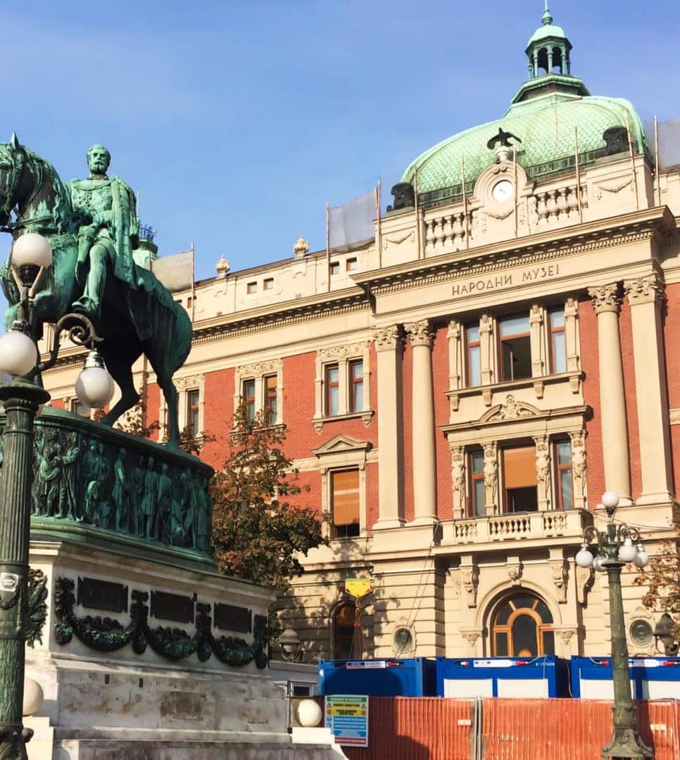 Prince-Mihailo-Monument man on statue of a horse with a large building in background