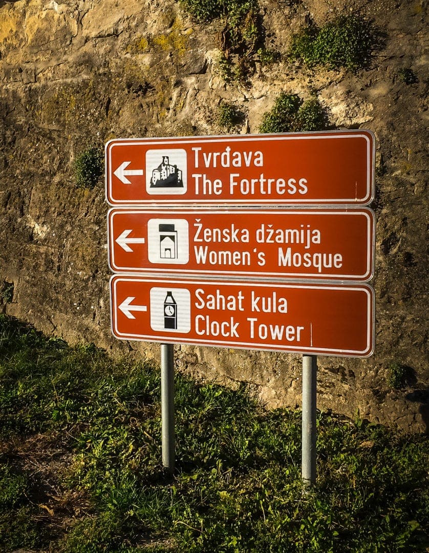 Sign in the town of Jajce, pointing towards tower, mosque and clock tower