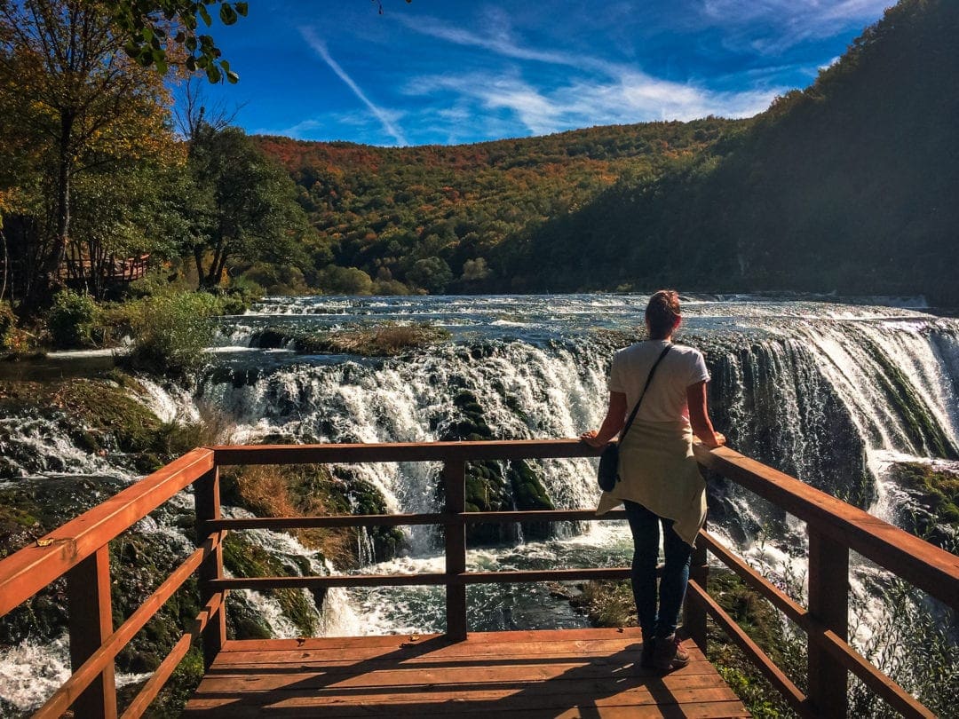 Shelley stood on viewing platform with Strbacki buk falls in the background, surrounded by green and yellow tree covered mountains