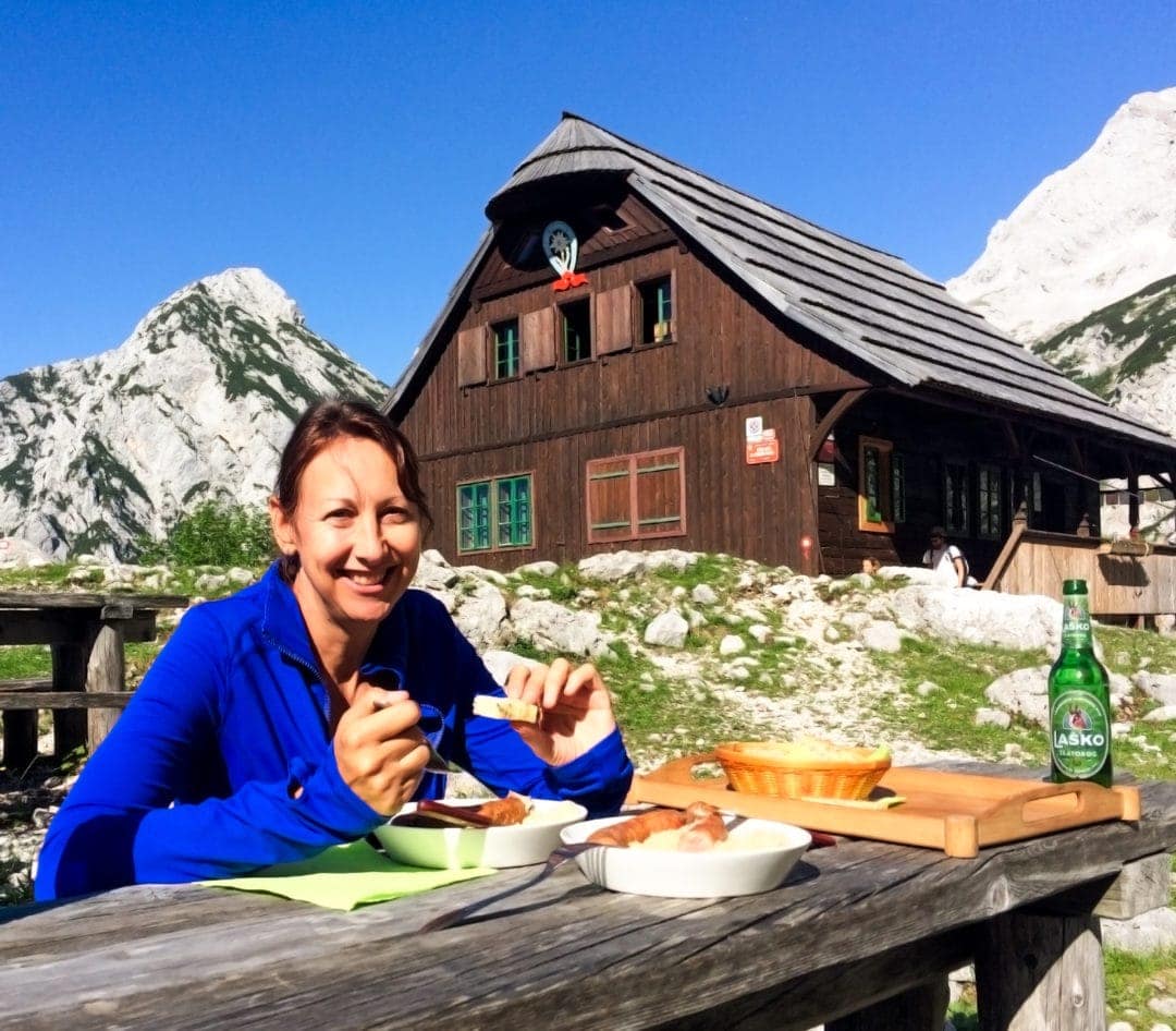 Ceska-Koca-Hut- Alpine hut in teh background with woman sat at table eatin g sauerkrat and sausages