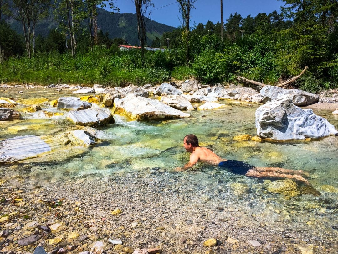 Ferlach-river-bathing - man in shallow with rocks stream 