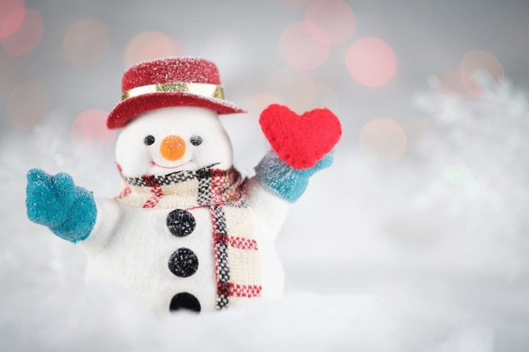 snowman in woolly hat and gloves holding a red heart