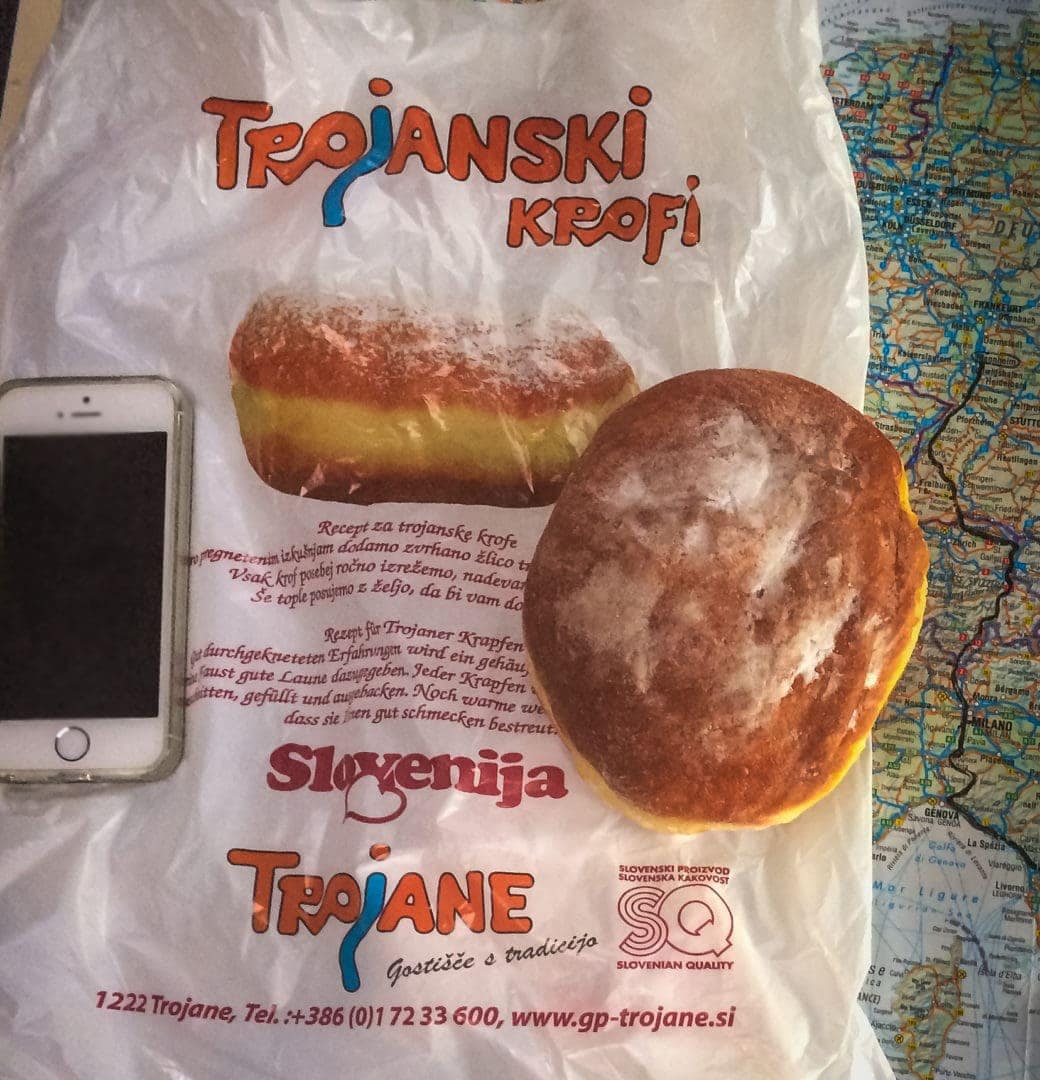 Doughnut on a paper bag that is bigger than a mobile phone