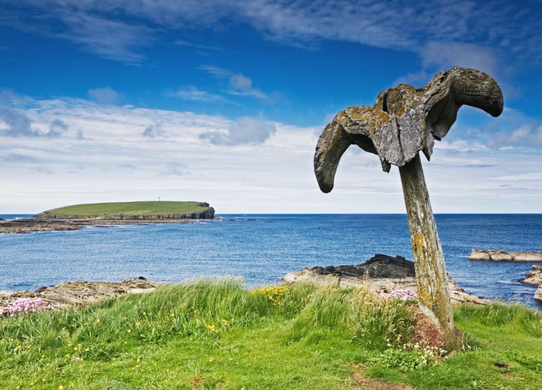whalebone on a pole beside the oceanwith brough of Birsay in the background