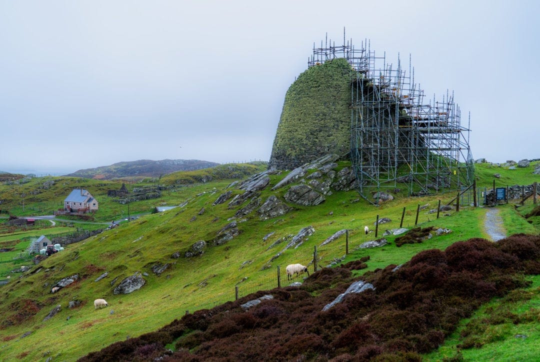Carloway Broch - a stone buuilding built in teh form of a wave with scaffolding around the outside