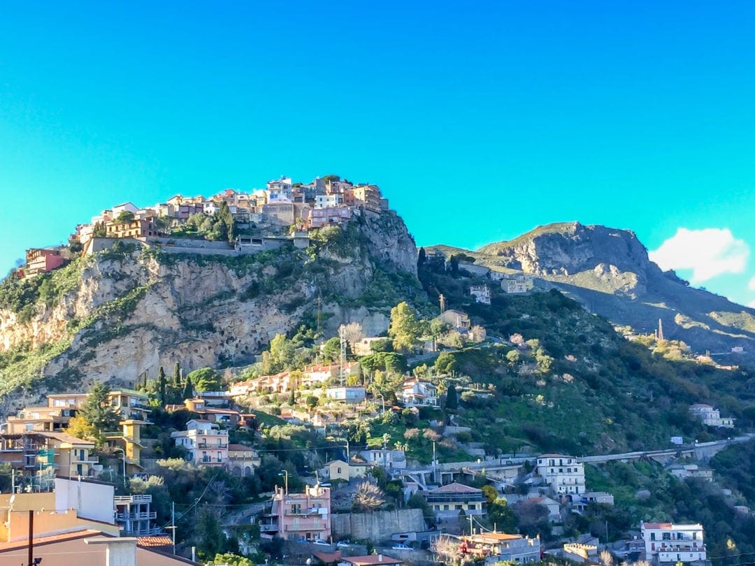 A mass of houses on the top of a cliff at Castelmora on our Sicily road trip