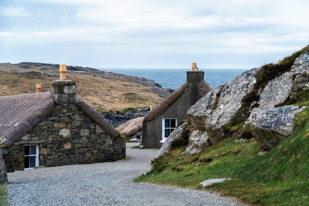 Gearrannan-Blackhouse-- a couple of thatched cottages with teh ocean in the background
