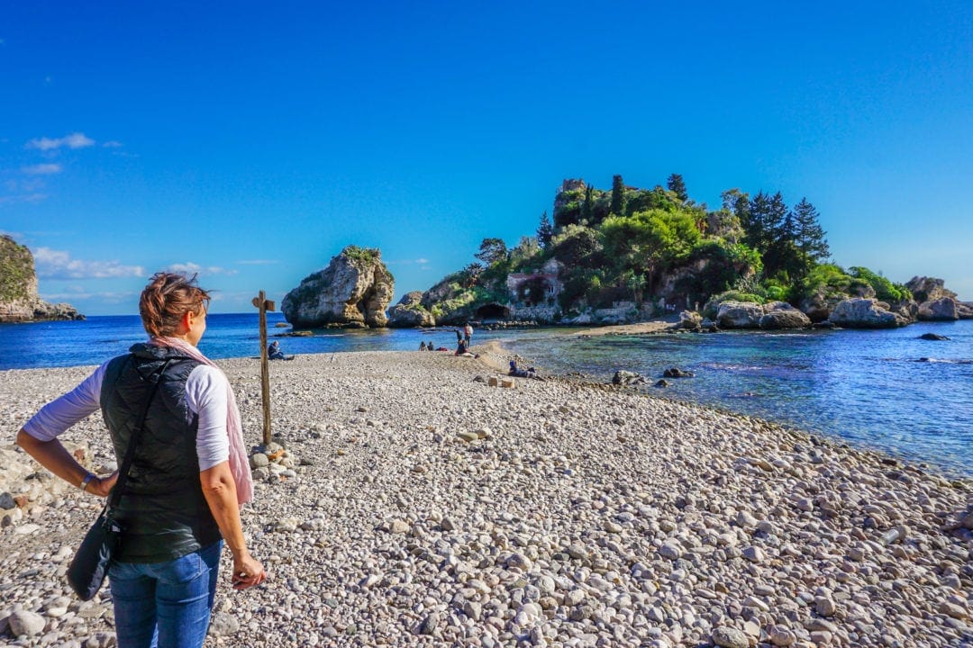 Shelley stood on beach looking at small island connected to main pebbly beach