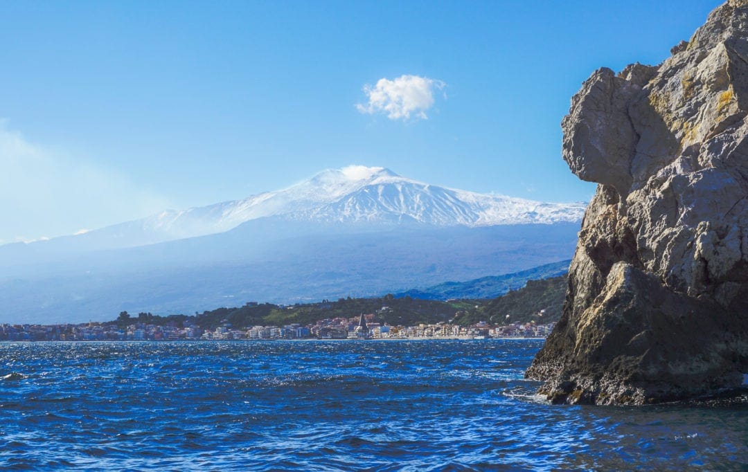 Image of snow capped mount Etna as seen from a boat in the bay at Taormina