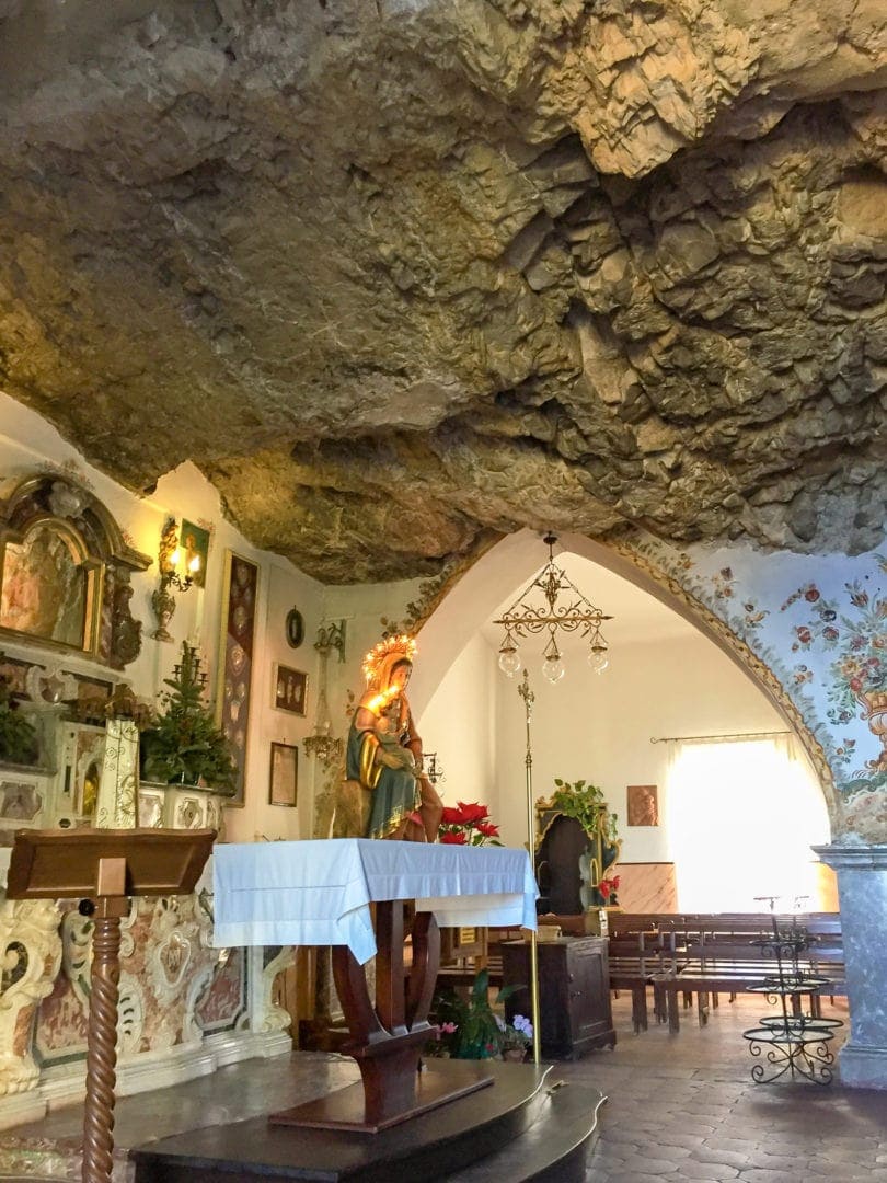 a church built into a rock with rock as the ceiling and white wash walls with fresco 