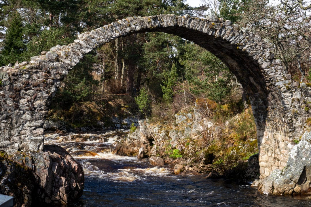 Old Packhorse stone bridge with high arch over a river 